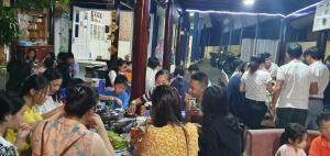 eine Gruppe von Menschen, die um einen Tisch mit Essen stehen in der Unterkunft Khách Sạn Minh Hồng in Long Hải