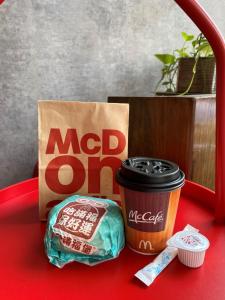 Um saco McDonald e uma chávena de café numa mesa vermelha. em Jin Spa Resort Hotel em Jinshan