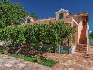 una casa con un árbol delante de ella en Charming holiday home with private pool en Donji Zemunik