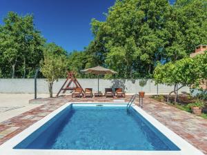 a swimming pool with chairs and an umbrella at Charming holiday home with private pool in Donji Zemunik