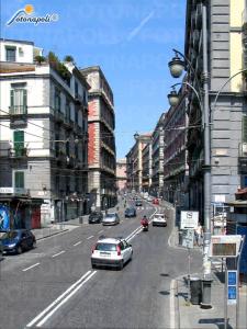 a street with cars driving down a city street with buildings at Maison Dante in Naples
