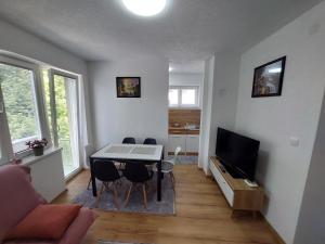 uma sala de estar com uma mesa e cadeiras e uma televisão em Apartman "MEDENI" em Bihać