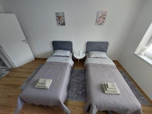 two twin beds in a room with a table at Apartman "MEDENI" in Bihać