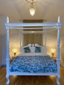 a bedroom with a blue bed with a white canopy at Boutique Hotel Postgården in Holsted