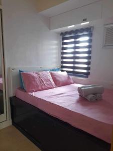 a bedroom with a bed with pink sheets and a window at 1 Bedroom US Embassy Roxas Blvd. Ermita Manila in Manila
