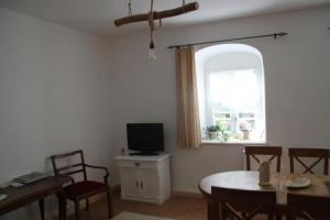 a living room with a table and a tv and a window at Hofmühle Pfaffroda-Ferienwohnung Am Mühlbach in Olbernhau