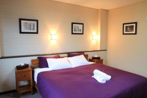 a bedroom with a purple bed with two towels on it at Morino Lodge - Myoko in Myoko