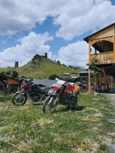 Omalo的住宿－A North Homestay，两辆摩托车停在草地上,后面有一座城堡