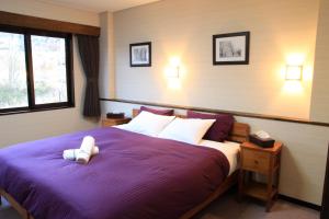 - une chambre dotée d'un lit violet avec un ours en peluche dans l'établissement Morino Lodge - Myoko, à Myōkō
