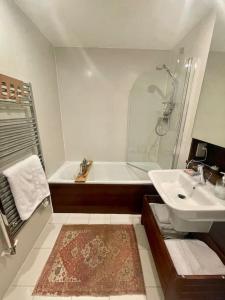 a bathroom with a bath tub and a sink at Modern 1 King Size Apartment in Angel near canal in London