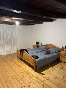 een slaapkamer met een bed en een houten vloer bij Puskás vendégház 