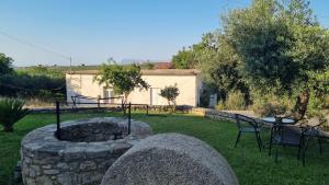 un patio trasero con una hoguera de piedra, una mesa y sillas en Casa Artemis, en Plátanos