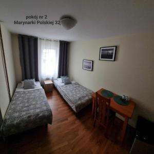ウストカにあるSyrenka Apartamentyのベッド2台とテーブルが備わるホテルルームです。