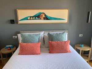 una cama blanca con almohadas y una foto de un perro en Above & Beyond Volos City Center Luxury Redefined, en Volos
