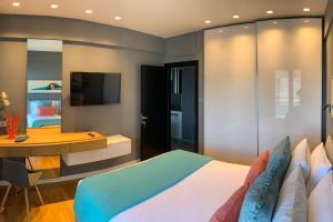 Dormitorio con cama, escritorio y TV en Above & Beyond Volos City Center Luxury Redefined, en Volos