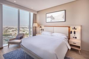 a bedroom with a large white bed and a chair at Four Points by Sheraton Jeddah Corniche in Jeddah