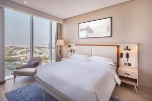 吉達的住宿－Four Points by Sheraton Jeddah Corniche，卧室配有一张白色大床和一把椅子