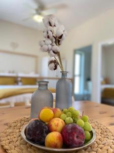 a plate of fruit on a table with two vases at The Roof in Kfar Blum