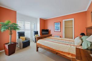 a bedroom with orange walls and a bed and a palm tree at The Tides by Ready Set Stay - BYO LINEN & TOWELS in Cowes