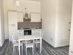 a white kitchen with a white table and chairs at Residenza Rogiò in Policoro