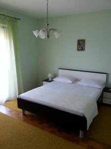 ein Schlafzimmer mit einem großen Bett und einem Kronleuchter in der Unterkunft Apartments Lukacic in Tkon