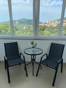 Duas cadeiras e uma mesa num quarto com janelas em Apartment Mare em Čunski