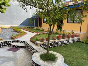 un jardin avec un arbre et un mur en pierre dans l'établissement Happy Home Guest House, à Pokhara