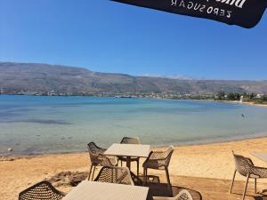 a table and chairs on a beach with the water at Antigoni Apartment in Souda