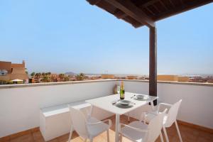 a white table and chairs on a balcony with a view at Luxury Ocean View - Carpe Mundi in Corralejo