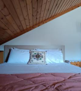 a bed with white pillows and a wooden ceiling at Cozy Loft with Fireplace & View in Metsovo