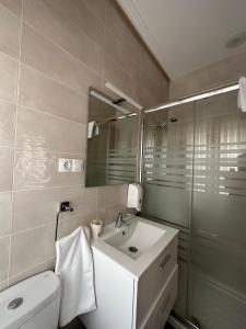 a bathroom with a sink and a toilet and a mirror at Hostal Restaurante Boccalino in León