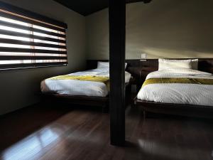 two beds in a bedroom with a window and wooden floors at 游月庵 in Inuyama