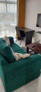 a green couch in a living room with a table at Cosy Studio with Workspace in Nairobi