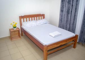 Ce lit se trouve dans un dortoir doté d'un cadre de lit en bois. dans l'établissement FAHARI .KE 3BR BY MTWAPA HOMESTAY, à Mombasa