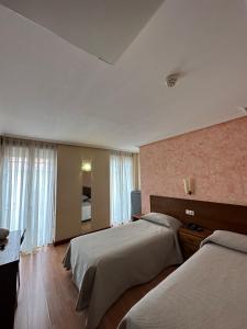 um quarto de hotel com duas camas e uma televisão em Hostal Restaurante Boccalino em León