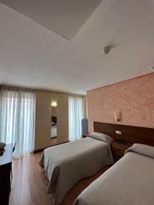 a hotel room with two beds and a television at Hostal Restaurante Boccalino in León +30 photos
