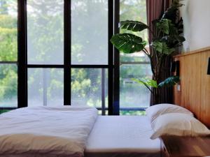 On My Way Taitung Hostel في مدينة تايتونج: غرفة نوم بسرير ونافذة كبيرة