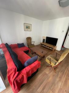 Sala de estar con cama roja y TV en Maison hyper-centre Bagnères de Luchon en Luchon