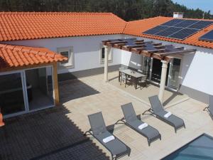 um pátio com cadeiras e painéis solares numa casa em Villa with private wellness and pool em Salir de Matos