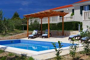 a swimming pool with a wooden pergola next to a house at Holiday Homes Oliva in Bol