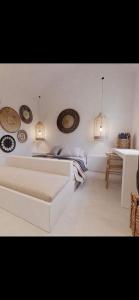 a white bedroom with a bed and some lights at Lejardin suites santorini in Pirgos