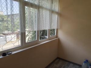 an empty room with two windows with white curtains at Мейкин in Osh