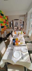 una mesa larga con platos y utensilios blancos. en Pensiunea Sergiu & Geanina, en Arad