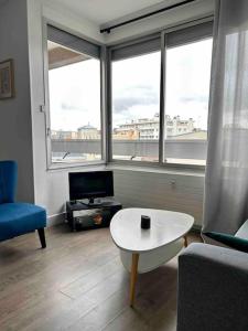 a living room with a table and a large window at Studio- avec parking- proche Cathedrale in Reims