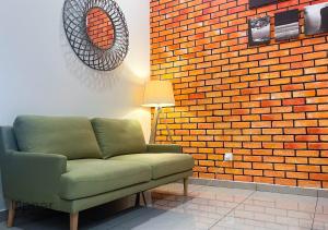 un sofá verde en una habitación con una pared de ladrillo en Upper Residence Homestay in Ujong Pasir Melaka, 4 bedrooms, 14pax en Melaka