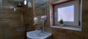 uma casa de banho com um lavatório, uma janela e um telefone em Pensiunea Sergiu & Geanina em Arad