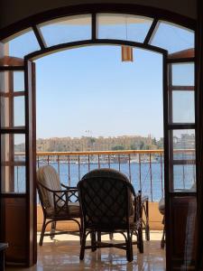 een balkon met 2 stoelen en uitzicht op het water bij Luxor Plaza House in Luxor
