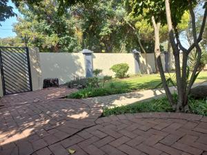 a brick walkway in a yard with a fence at Ikhutse Manor Guesthouse in Mahikeng