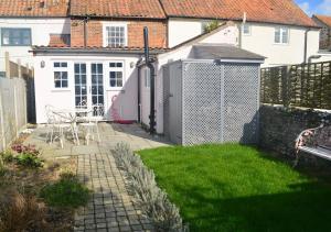 a backyard with a fence and a table and chairs at Skylarks - Cley next the Sea - Crabpot Cottages. in Cley next the Sea
