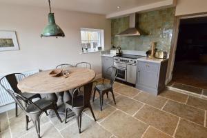 a kitchen with a wooden table and chairs in a kitchen at Skylarks - Cley next the Sea - Crabpot Cottages. in Cley next the Sea